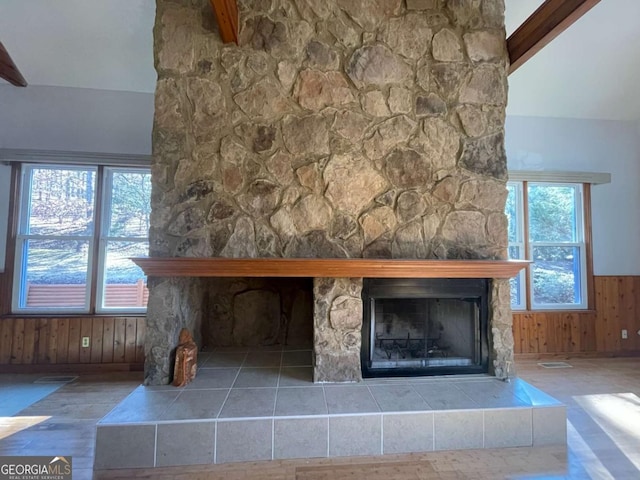 room details with beamed ceiling, wooden walls, and a stone fireplace