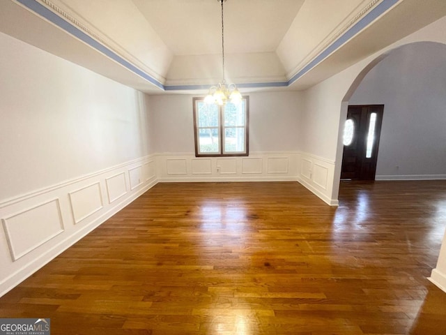 unfurnished dining area with dark hardwood / wood-style floors, a raised ceiling, and a chandelier