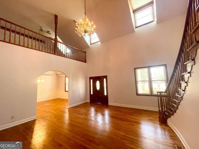 unfurnished living room featuring dark wood-type flooring, an inviting chandelier, and a high ceiling