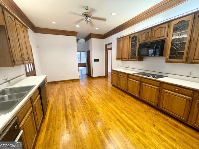 kitchen featuring sink, light wood-type flooring, ornamental molding, ceiling fan, and black appliances