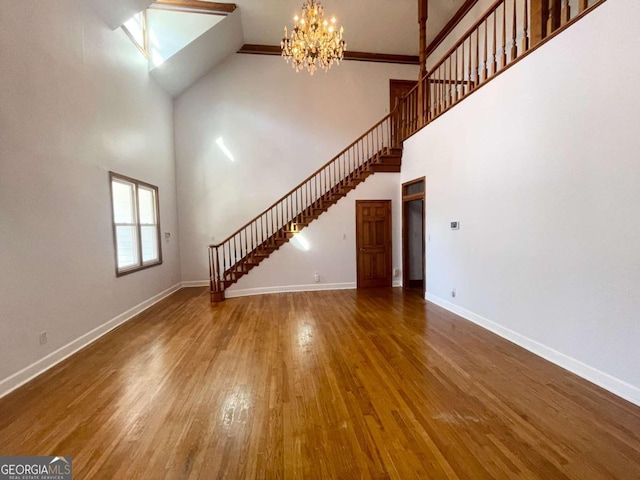 unfurnished living room with an inviting chandelier, hardwood / wood-style floors, and a high ceiling