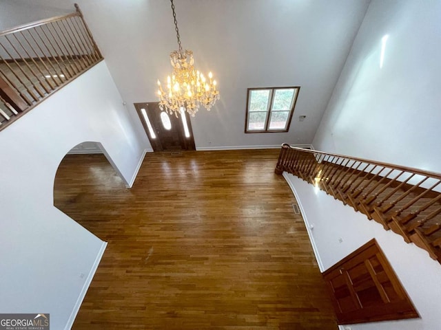 foyer featuring dark wood-type flooring, a towering ceiling, and a chandelier