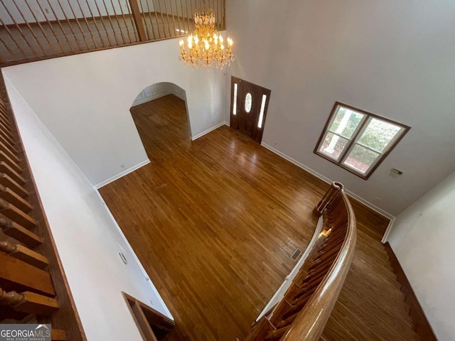 interior space featuring dark wood-type flooring, a towering ceiling, and a chandelier