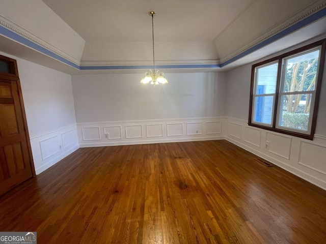 unfurnished dining area featuring dark hardwood / wood-style flooring, a notable chandelier, and a tray ceiling