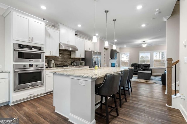 kitchen with stainless steel appliances, an island with sink, and white cabinets