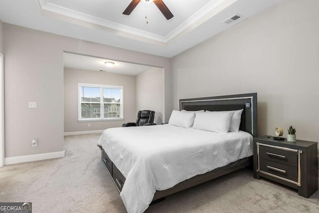 bedroom with crown molding, light carpet, ceiling fan, and a tray ceiling