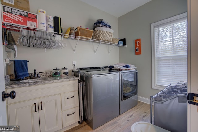 laundry room featuring sink, washing machine and clothes dryer, and light wood-type flooring