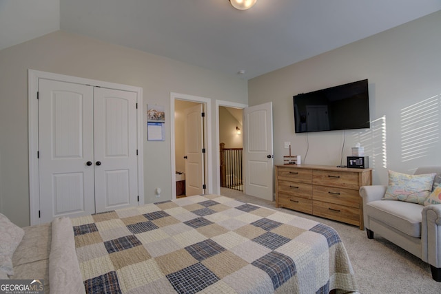 bedroom with vaulted ceiling, light colored carpet, and a closet