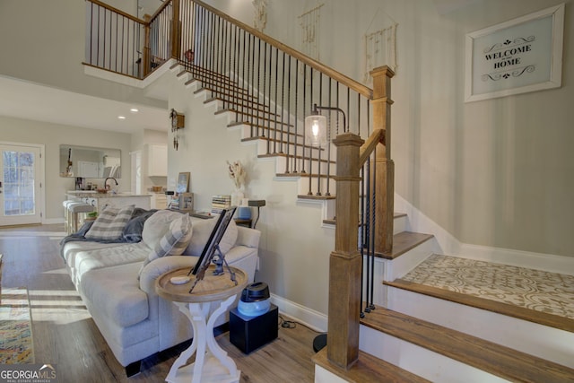 staircase with a towering ceiling and wood-type flooring