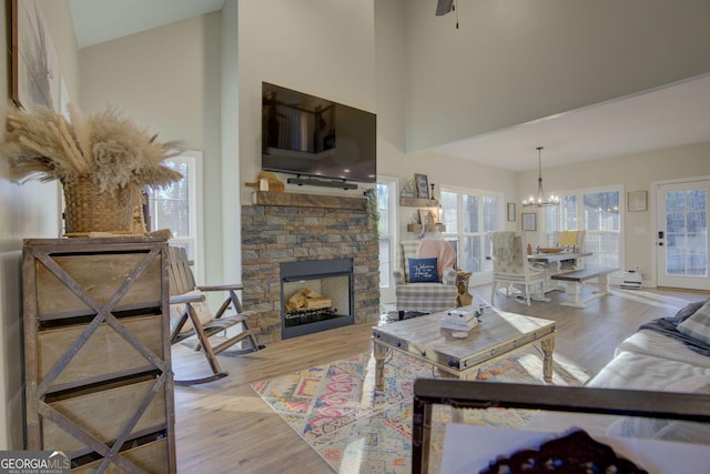 living room with a stone fireplace, light hardwood / wood-style floors, and a high ceiling