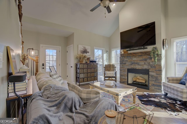 living room featuring hardwood / wood-style flooring, a fireplace, high vaulted ceiling, and ceiling fan