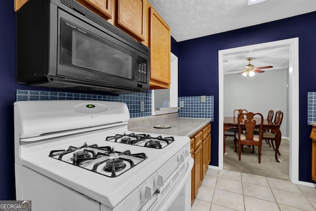 kitchen with light tile patterned floors, gas range gas stove, ceiling fan, tasteful backsplash, and a textured ceiling