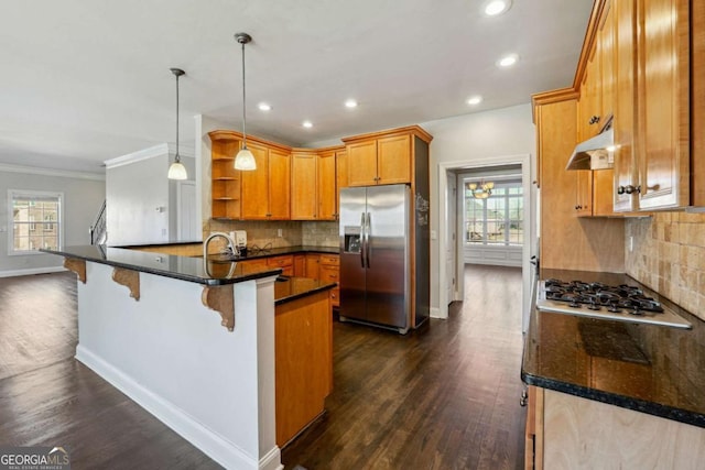 kitchen with decorative light fixtures, appliances with stainless steel finishes, dark hardwood / wood-style flooring, kitchen peninsula, and a kitchen breakfast bar