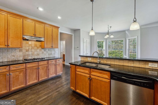 kitchen with stainless steel appliances, sink, dark stone countertops, and decorative light fixtures