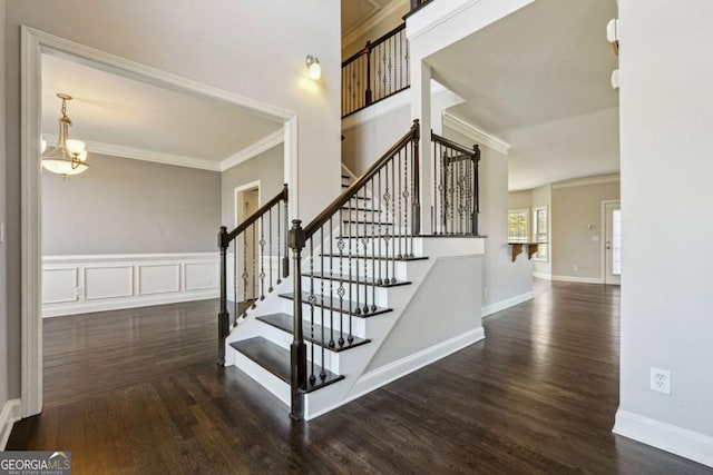 stairway featuring hardwood / wood-style floors, crown molding, and a chandelier