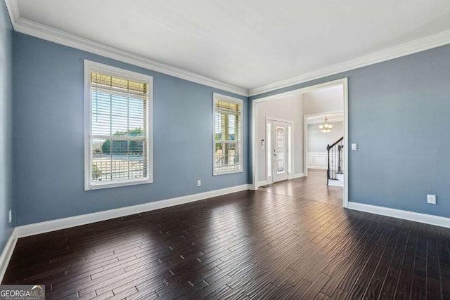 spare room featuring dark wood-type flooring, ornamental molding, and a wealth of natural light