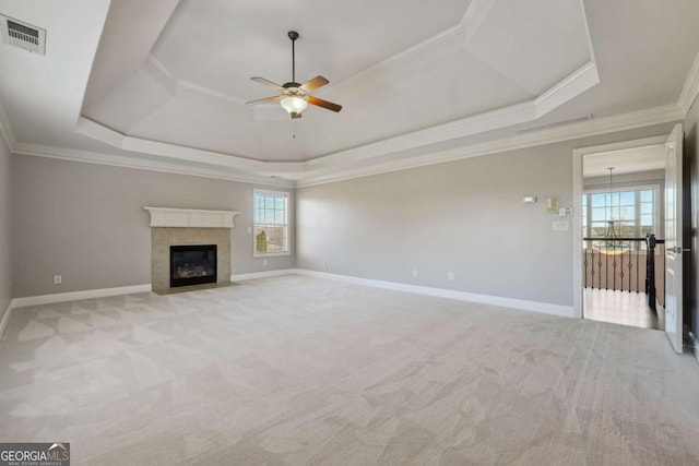 unfurnished living room with ornamental molding, light colored carpet, a raised ceiling, and ceiling fan