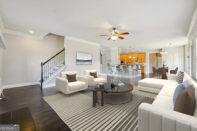 living room with ornamental molding, ceiling fan with notable chandelier, and dark hardwood / wood-style flooring