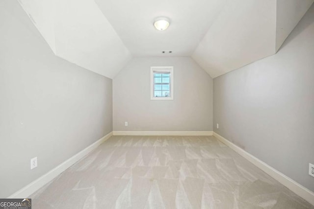 additional living space featuring light carpet and vaulted ceiling