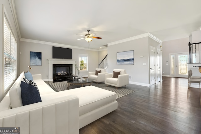 living room with a tiled fireplace, ornamental molding, dark hardwood / wood-style floors, and ceiling fan