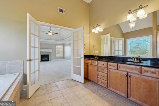 bathroom featuring tile patterned flooring, vanity, ceiling fan, tiled tub, and french doors