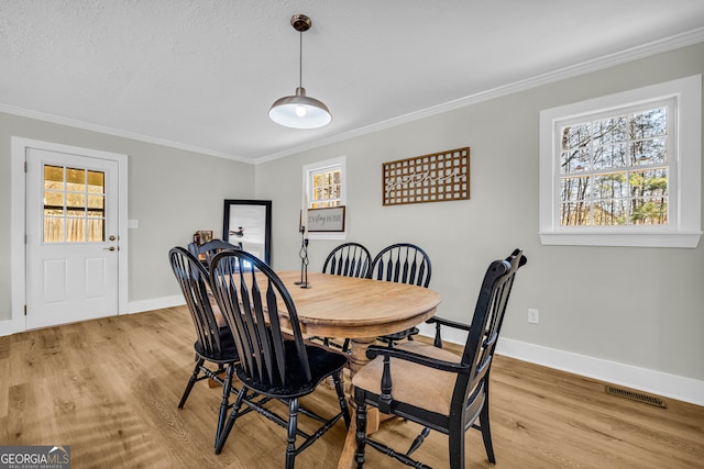 dining room featuring crown molding, a textured ceiling, and light hardwood / wood-style floors