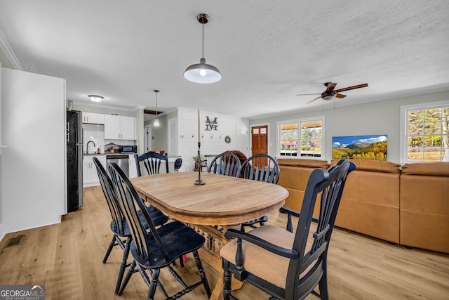 dining space with a healthy amount of sunlight, a textured ceiling, and light wood-type flooring