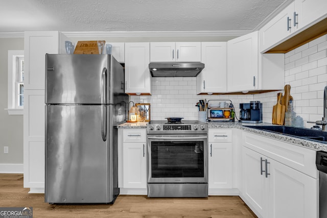 kitchen with sink, white cabinetry, appliances with stainless steel finishes, light stone countertops, and light hardwood / wood-style floors