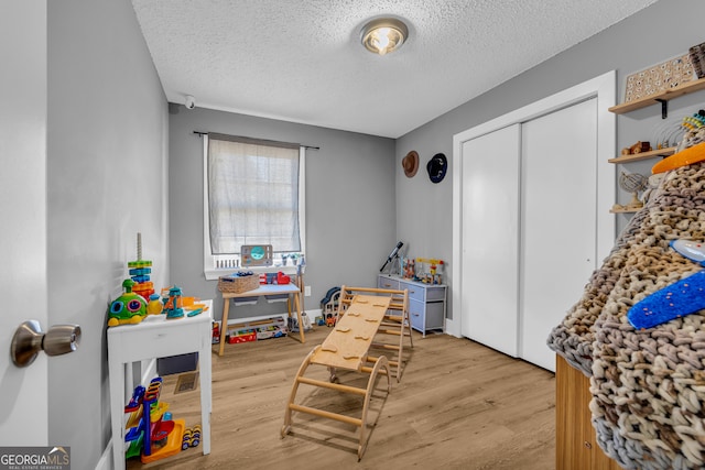 rec room featuring a textured ceiling and light hardwood / wood-style floors