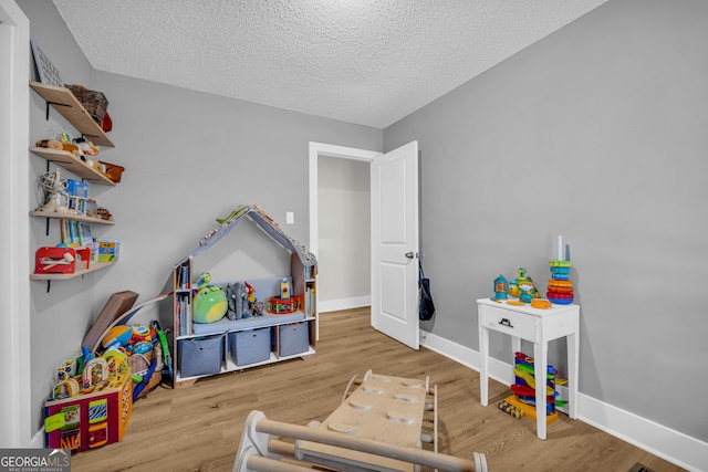 game room featuring a textured ceiling and light wood-type flooring