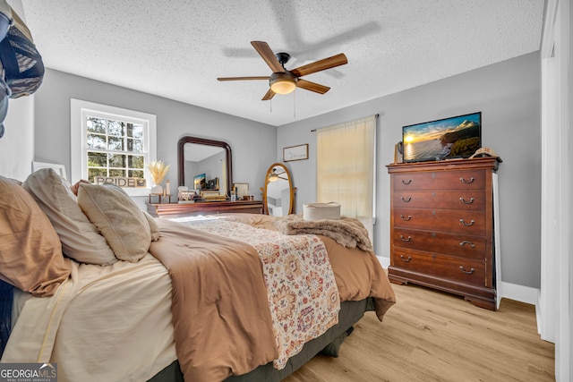 bedroom featuring ceiling fan, a textured ceiling, and light hardwood / wood-style flooring