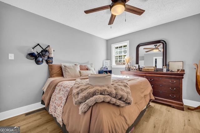 bedroom with ceiling fan, a textured ceiling, and light wood-type flooring