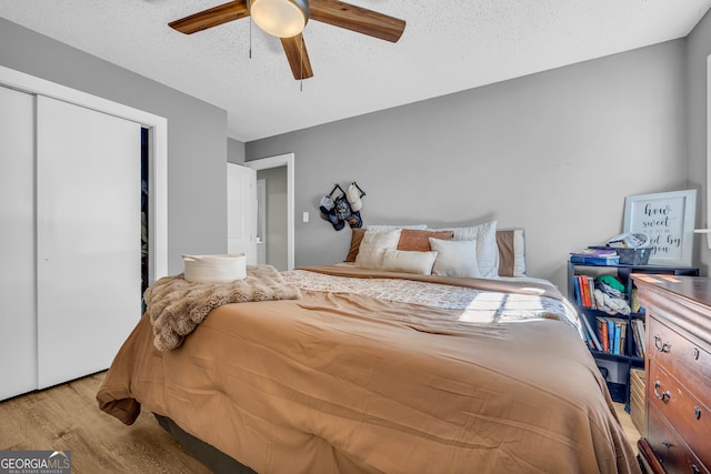 bedroom featuring a closet, ceiling fan, light hardwood / wood-style floors, and a textured ceiling