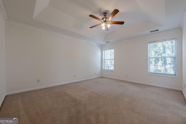 unfurnished room with ornamental molding, light colored carpet, a raised ceiling, and ceiling fan