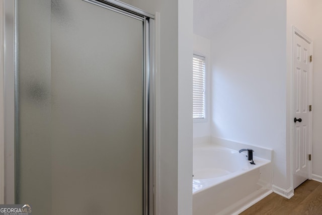 bathroom featuring hardwood / wood-style flooring and shower with separate bathtub