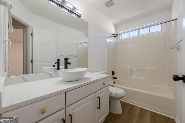 full bathroom with shower / bath combination, hardwood / wood-style floors, vanity, a textured ceiling, and toilet