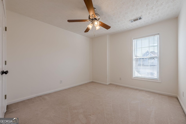 unfurnished room featuring ceiling fan, light colored carpet, and a textured ceiling