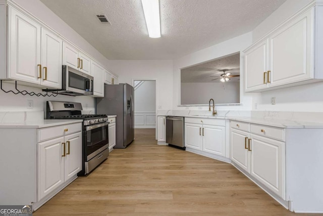 kitchen with white cabinetry, appliances with stainless steel finishes, light hardwood / wood-style floors, and sink