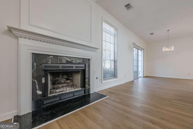 interior space with an inviting chandelier, a high end fireplace, and wood-type flooring