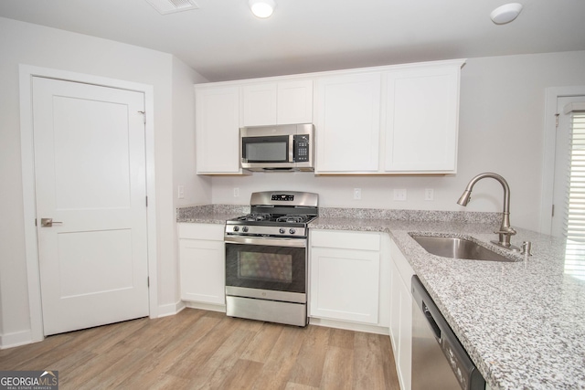 kitchen with sink, light hardwood / wood-style flooring, white cabinets, and appliances with stainless steel finishes