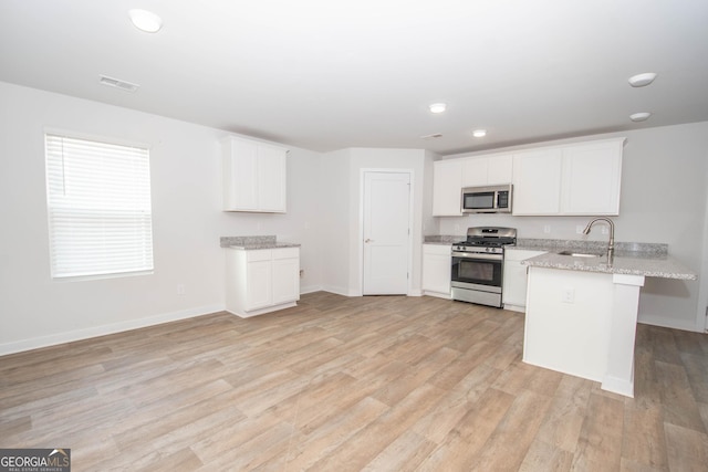 kitchen with white cabinetry, appliances with stainless steel finishes, sink, and light stone counters