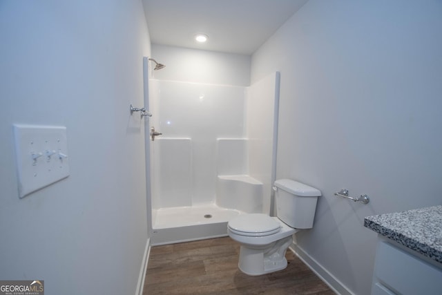 bathroom featuring hardwood / wood-style flooring, a shower, vanity, and toilet