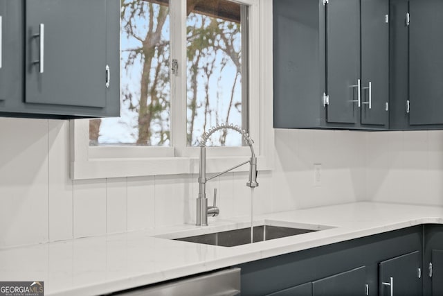 kitchen with gray cabinetry, decorative backsplash, a sink, and a healthy amount of sunlight