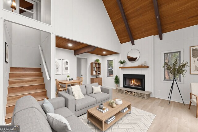 unfurnished living room with high vaulted ceiling, a large fireplace, wood ceiling, beam ceiling, and light hardwood / wood-style flooring