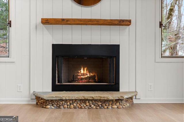 interior details featuring a warm lit fireplace, wood finished floors, and baseboards