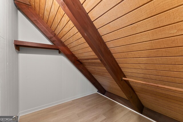 additional living space featuring hardwood / wood-style flooring, beam ceiling, and wooden ceiling