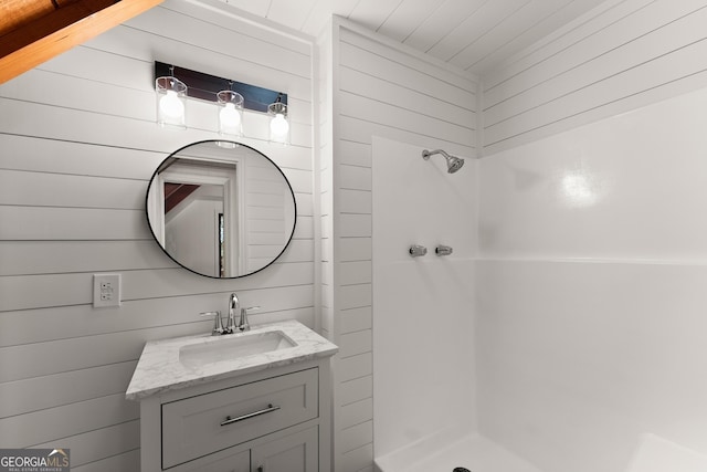 bathroom featuring a stall shower, wooden walls, and vanity