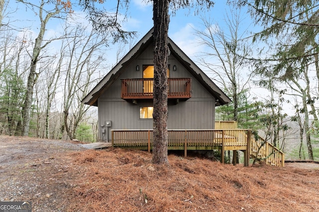 back of property with a wooden deck and a balcony