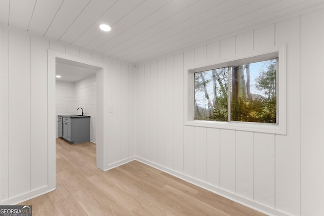 empty room featuring recessed lighting, baseboards, a sink, and light wood finished floors