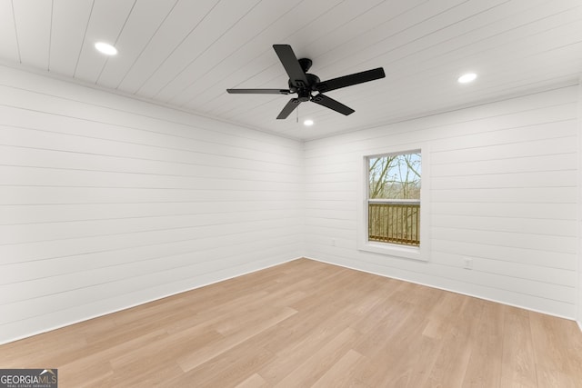 empty room featuring a ceiling fan, light wood-type flooring, wooden walls, and recessed lighting